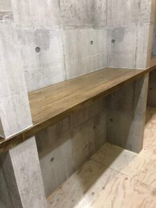 壁面のコンクリートデザインのクロスと作り付けの棚